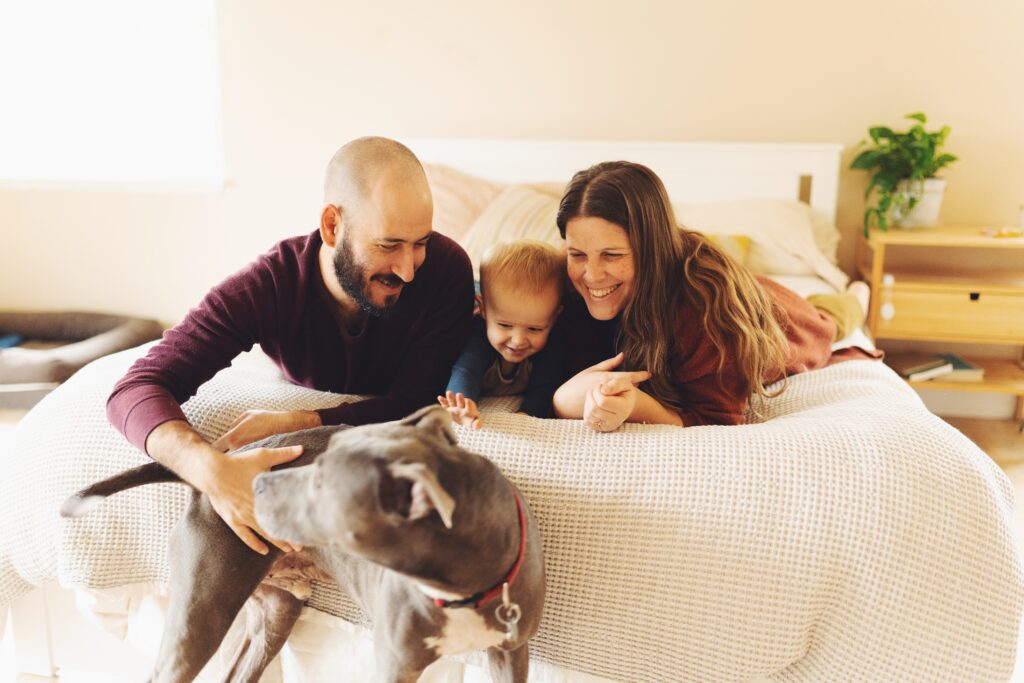 family laughing together on bed wearing maroon and dark orange outfits