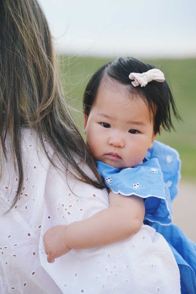 Portrait of young girl on her mom's shoulder at the Bluffs Regional Park in Lone Tree